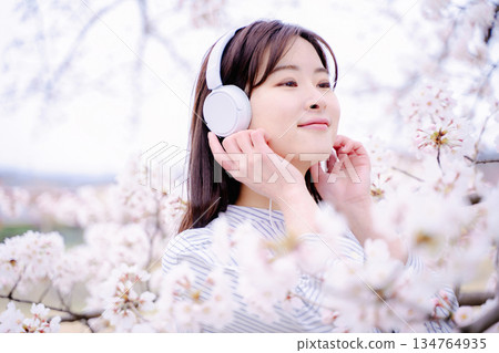 年輕女子在櫻花樹下欣賞音樂 134764935