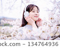 Young woman enjoying music under the cherry blossom tree 134764936