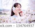 Young woman enjoying music under the cherry blossom tree 134764937
