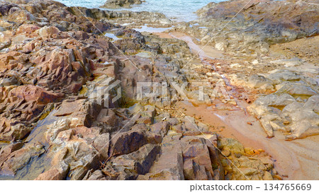 Rugged Coastal Rock Formations and Sandy Shore 134765669