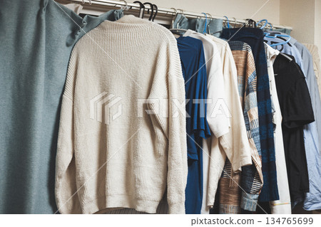 Men's clothes drying indoors on the curtain rail: knitwear and shirts lined up Men's clothes drying indoors on the curtain rail: knitwear and shirts lined up 134765699