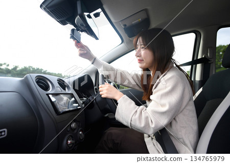 一位年輕女子正在查看她車上的行車記錄器。 一位年輕女子正在查看她車上的行車記錄器。 134765979