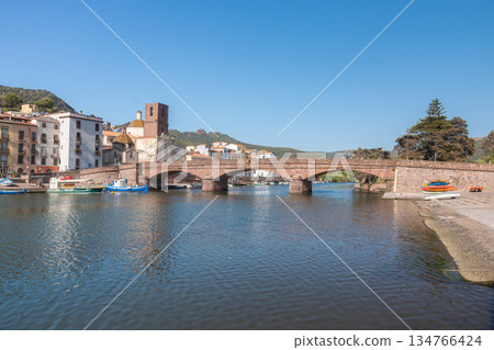 A historic stone bridge crossing a calm river with reflections on the water. Soft daylight and natural surroundings create a serene travel and landscape scene, Bosa, Italien 134766424