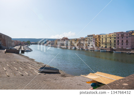 A calm riverside promenade with clear reflections on the water under soft daylight. Urban buildings line the shore, creating a peaceful waterfront city scene suitable for travel, architecture and 134766432