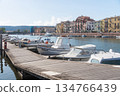 Peaceful marina with small boats moored along a wooden pier on a sunny day. Calm water, bright light and relaxed coastal atmosphere make this scene suitable for travel, tourism and seaside lifestyle 134766439