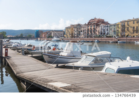 Peaceful marina with small boats moored along a wooden pier on a sunny day. Calm water, bright light and relaxed coastal atmosphere make this scene suitable for travel, tourism and seaside lifestyle Peaceful marina with small boats moored along a wooden pier on a sunny day. Calm water, bright light and relaxed coastal atmosphere make this scene suitable for travel, tourism and seaside lifestyle 134766439