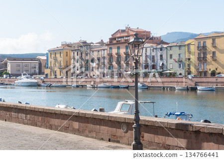 Colorful residential buildings line the waterfront of a coastal European town. Boats, calm water and warm daylight create a relaxed seaside travel mood, Bosa, Italien Colorful residential buildings line the waterfront of a coastal European town. Boats, calm water and warm daylight create a relaxed seaside travel mood, Bosa, Italien 134766441