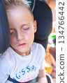 Close-up of a sleeping child in a car seat during a daytime ride. Natural light highlights the peaceful expression and travel setting. Editorial image depicting real moments and family life 134766442