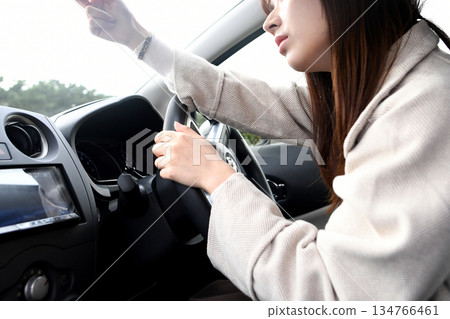 A young Asian woman with an anxious expression checking the dashcam in her car A young Asian woman with an anxious expression checking the dashcam in her car 134766461