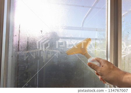 一名工人正在使用除露刮水器清除水滴。 一名工人正在使用除露刮水器清除水滴。 134767007