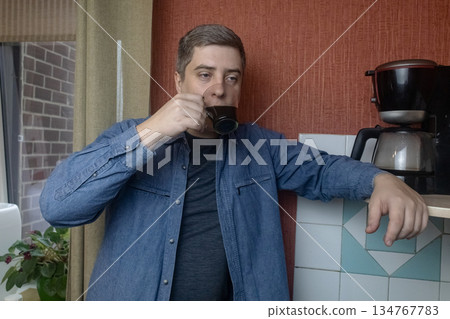 Man preparing fresh coffee at home using an electric coffee maker. Casual morning routine in a cozy kitchen, everyday lifestyle, simple domestic moment, authentic home brewing scene. Man preparing fresh coffee at home using an electric coffee maker. Casual morning routine in a cozy kitchen, everyday lifestyle, simple domestic moment, authentic home brewing scene. 134767783