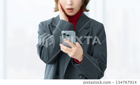 一位女士/女商人對她的智慧型手機螢幕感到驚訝 134767914