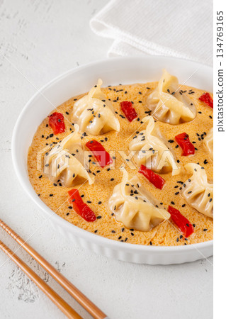Steamed gyoza dumplings in creamy Tom Yum sauce with sesame garnish 134769165