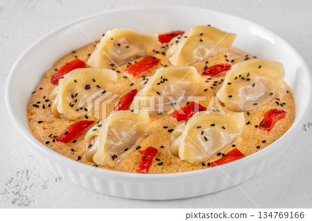 Steamed gyoza dumplings in creamy Tom Yum sauce with sesame garnish Steamed gyoza dumplings in creamy Tom Yum sauce with sesame garnish 134769166