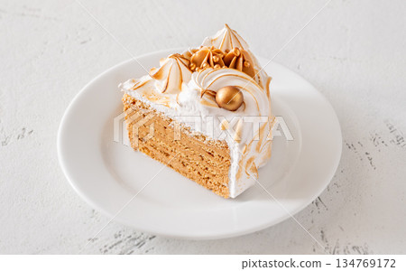 Slice of Medovik honey cake with toasted meringue and golden garnish 134769172