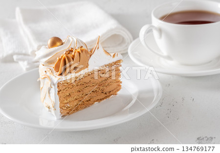 Slice of Medovik honey cake with toasted meringue and golden garnish 134769177