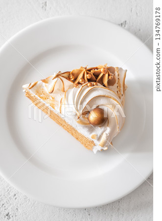 Slice of Medovik honey cake with toasted meringue and golden garnish 134769178