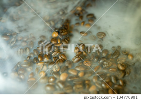 Close-up of roasted coffee beans with soft steam and haze, dramatic warm lighting, rich texture background for cafe and gourmet themes Close-up of roasted coffee beans with soft steam and haze, dramatic warm lighting, rich texture background for cafe and gourmet themes 134770991
