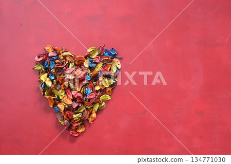 A heart of multicolored, dried rose petals on a burgundy background. Valentines Day card, March 8, Mothers Day. Top view.. A heart of multicolored, dried rose petals on a burgundy background. Valentines Day card, March 8, Mothers Day. Top view.. 134771030