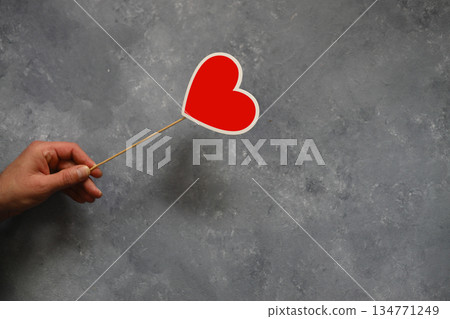 A man 's hand with a red heart symbol on a wooden background, copyspace 134771249
