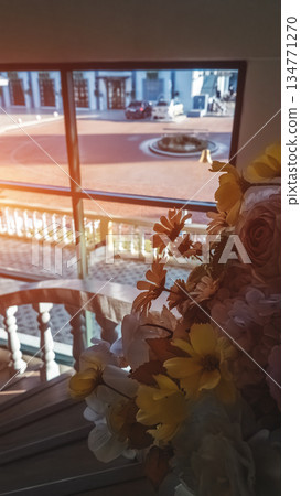 Bouquet flowers by window overlooking urban street sunlight, Floral arrangement indoor view city scene warm light Bouquet flowers by window overlooking urban street sunlight, Floral arrangement indoor view city scene warm light 134771270