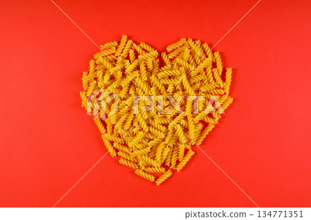 Pasta in the shape of a heart on a red background. Pasta in the shape of a heart on a red background. 134771351