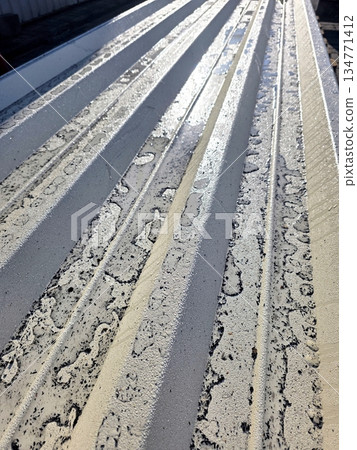 Corrugated Metal Sheet With Water Droplets on Surface Shines in Afternoon Sunlight 134771412