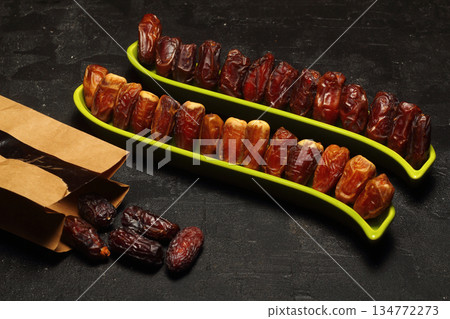 Dried dates on a wooden table in silver dishes close-up. Composition of dried dates in ramadan dish Dried dates on a wooden table in silver dishes close-up. Composition of dried dates in ramadan dish 134772273