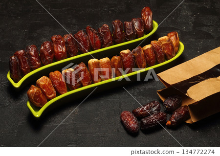 Dried dates on a wooden table in silver dishes close-up. Composition of dried dates in ramadan dish Dried dates on a wooden table in silver dishes close-up. Composition of dried dates in ramadan dish 134772274