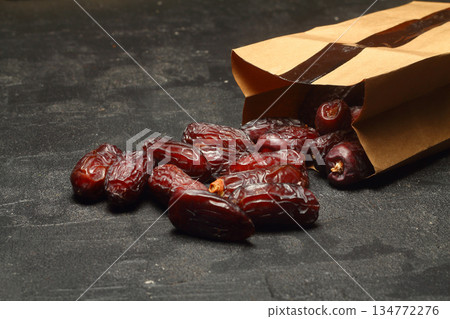 Dried dates on a wooden table in silver dishes close-up. Composition of dried dates in ramadan dish Dried dates on a wooden table in silver dishes close-up. Composition of dried dates in ramadan dish 134772276