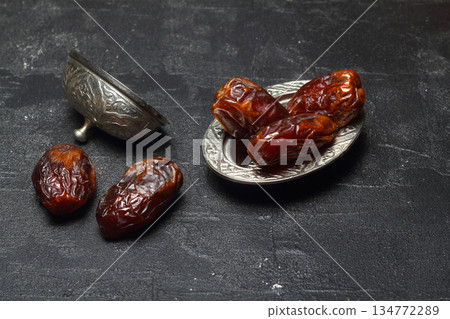 Dried dates on a wooden table in silver dishes close-up. Composition of dried dates in ramadan dish 134772289