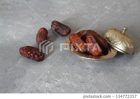 Dried dates on a wooden table in silver dishes close-up. Composition of dried dates in ramadan dish Dried dates on a wooden table in silver dishes close-up. Composition of dried dates in ramadan dish 134772357