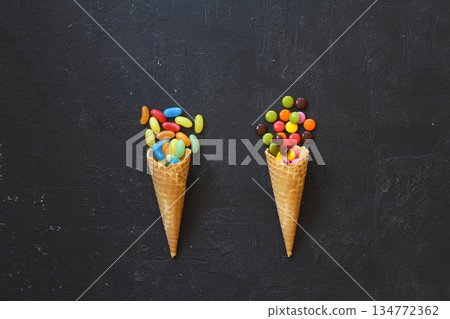 Top view of ice cream cone with colorful candy on the black background Top view of ice cream cone with colorful candy on the black background 134772362