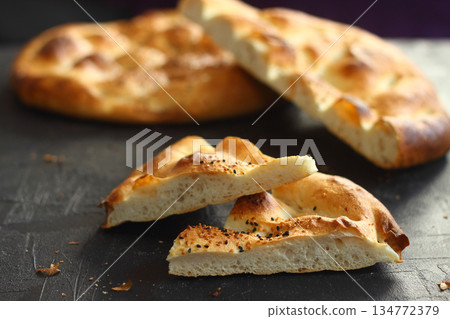 Slices of Ramadan Pita (Ramazan Pidesi) Traditional Turkish bread for holy month Ramadan on black background Slices of Ramadan Pita (Ramazan Pidesi) Traditional Turkish bread for holy month Ramadan on black background 134772379