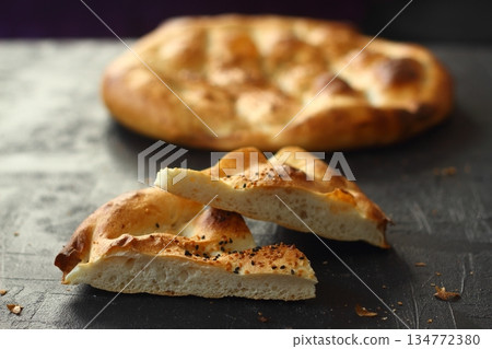 Slices of Ramadan Pita (Ramazan Pidesi) Traditional Turkish bread for holy month Ramadan on black background Slices of Ramadan Pita (Ramazan Pidesi) Traditional Turkish bread for holy month Ramadan on black background 134772380