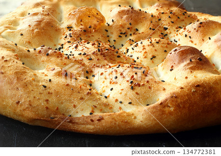 Slices of Ramadan Pita (Ramazan Pidesi) Traditional Turkish bread for holy month Ramadan on black background Slices of Ramadan Pita (Ramazan Pidesi) Traditional Turkish bread for holy month Ramadan on black background 134772381