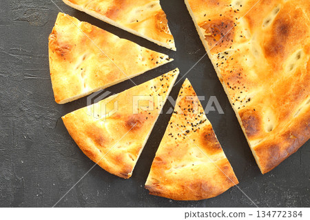 Slices of Ramadan Pita (Ramazan Pidesi) Traditional Turkish bread for holy month Ramadan on black background Slices of Ramadan Pita (Ramazan Pidesi) Traditional Turkish bread for holy month Ramadan on black background 134772384