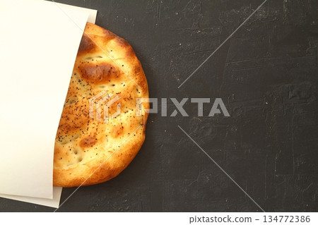 Slices of Ramadan Pita (Ramazan Pidesi) Traditional Turkish bread for holy month Ramadan on black background Slices of Ramadan Pita (Ramazan Pidesi) Traditional Turkish bread for holy month Ramadan on black background 134772386