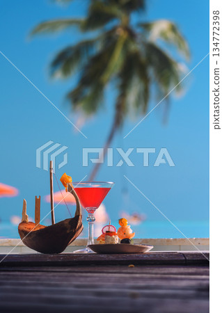 Tropical luxury cocktail with fruits by the pool with palm tree and see background Tropical luxury cocktail with fruits by the pool with palm tree and see background 134772398