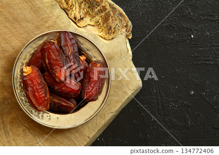 Dried dates on a wooden table in silver dishes close-up. Composition of dried dates in ramadan dish Dried dates on a wooden table in silver dishes close-up. Composition of dried dates in ramadan dish 134772406