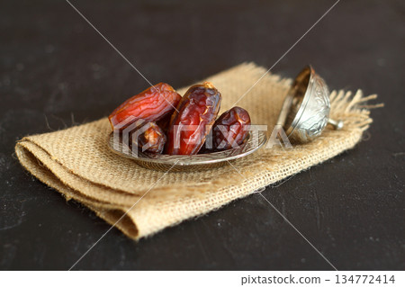 Dried dates on a wooden table in silver dishes close-up. Composition of dried dates in ramadan dish Dried dates on a wooden table in silver dishes close-up. Composition of dried dates in ramadan dish 134772414