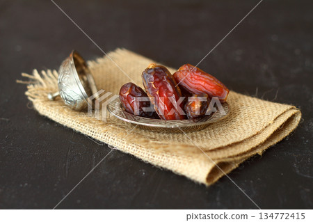 Dried dates on a wooden table in silver dishes close-up. Composition of dried dates in ramadan dish Dried dates on a wooden table in silver dishes close-up. Composition of dried dates in ramadan dish 134772415