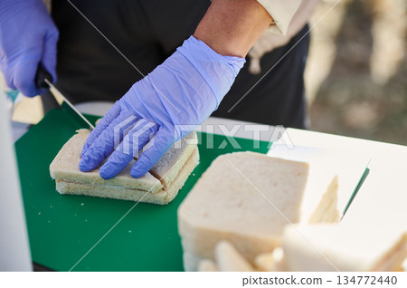 Food Safety Worker Preparing Sandwich On Green Cutting Board For Service Food Safety Worker Preparing Sandwich On Green Cutting Board For Service 134772440