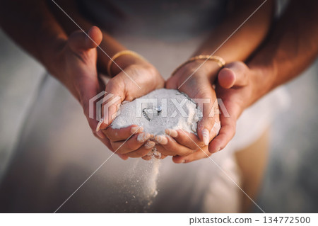 Romantic engagement on the beach: Couple holding white sand with a diamond ring during sunset 134772500
