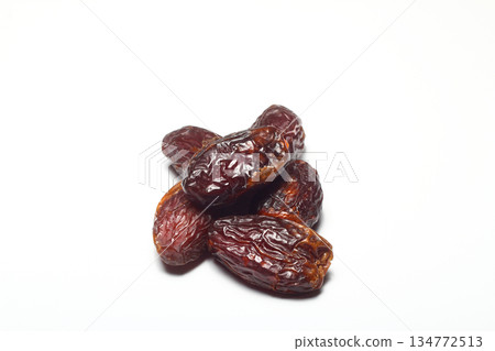 Dates on a white background. Dried fruits. Dried dates lie next to each other Dates on a white background. Dried fruits. Dried dates lie next to each other 134772513