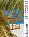 Luxury tropical resort with white sand beach, thatched umbrella and water villas over turquoise ocean 134772518