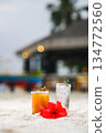 Tropical beach cocktails and red hibiscus flower on white sand with blurred resort background 134772560