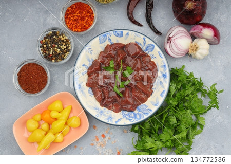 Cut raw beef liver with onions, spices, chili peppers and dill on wooden table, flat lay 134772586