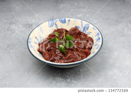 Cut raw beef liver with onions, spices, chili peppers and dill on wooden table, flat lay Cut raw beef liver with onions, spices, chili peppers and dill on wooden table, flat lay 134772589