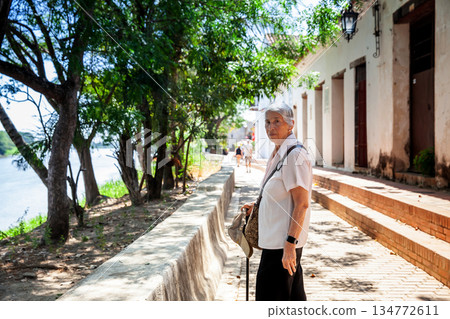 Senior travel concept. Senior woman walking at the beautiful streets of the colonial Heritage Town of Santa Cruz de Mompox in Colombia. 134772611